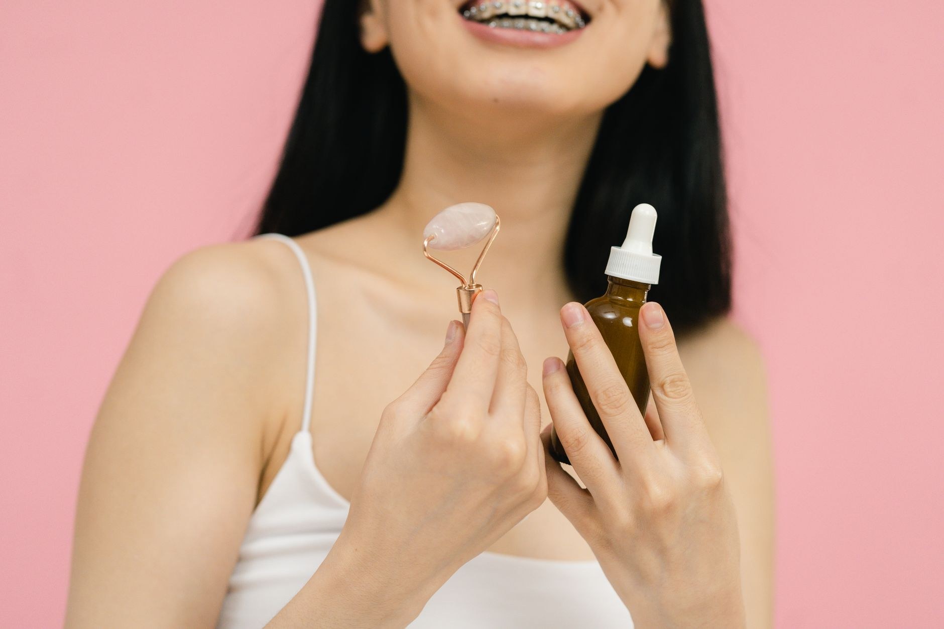Client holding a facial roller and a herbal serum for skin rejuvenation
